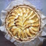 Apfelkuchen mit gebratenen Apfelscheiben, auf Backpapier präsentiert, von oben gesehen.