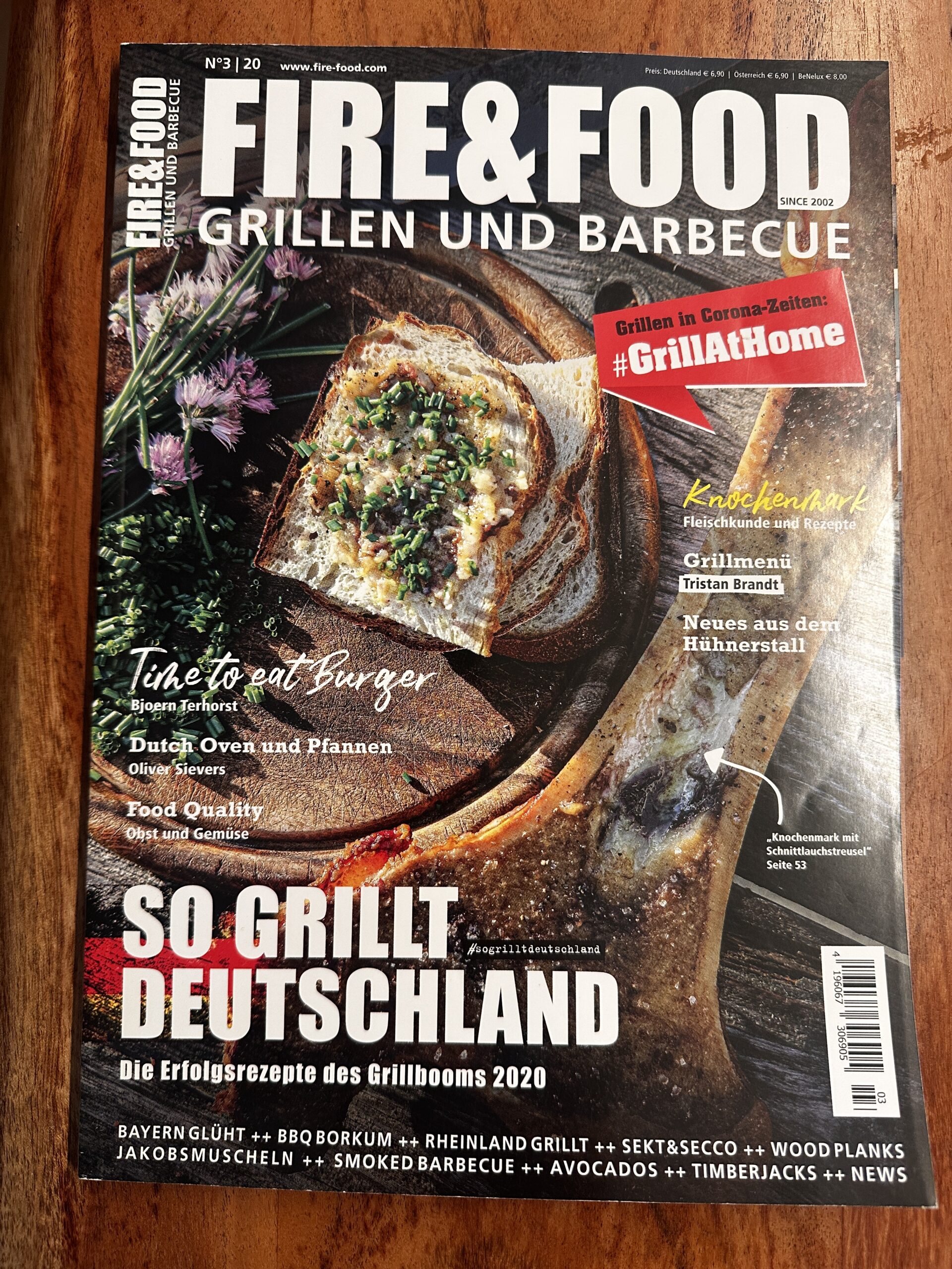 Fire&Food-2 Magazin über Grillen mit einem belegten Brot auf Holzbrett und Texten zu Rezepten und Grilltrends in Deutschland.