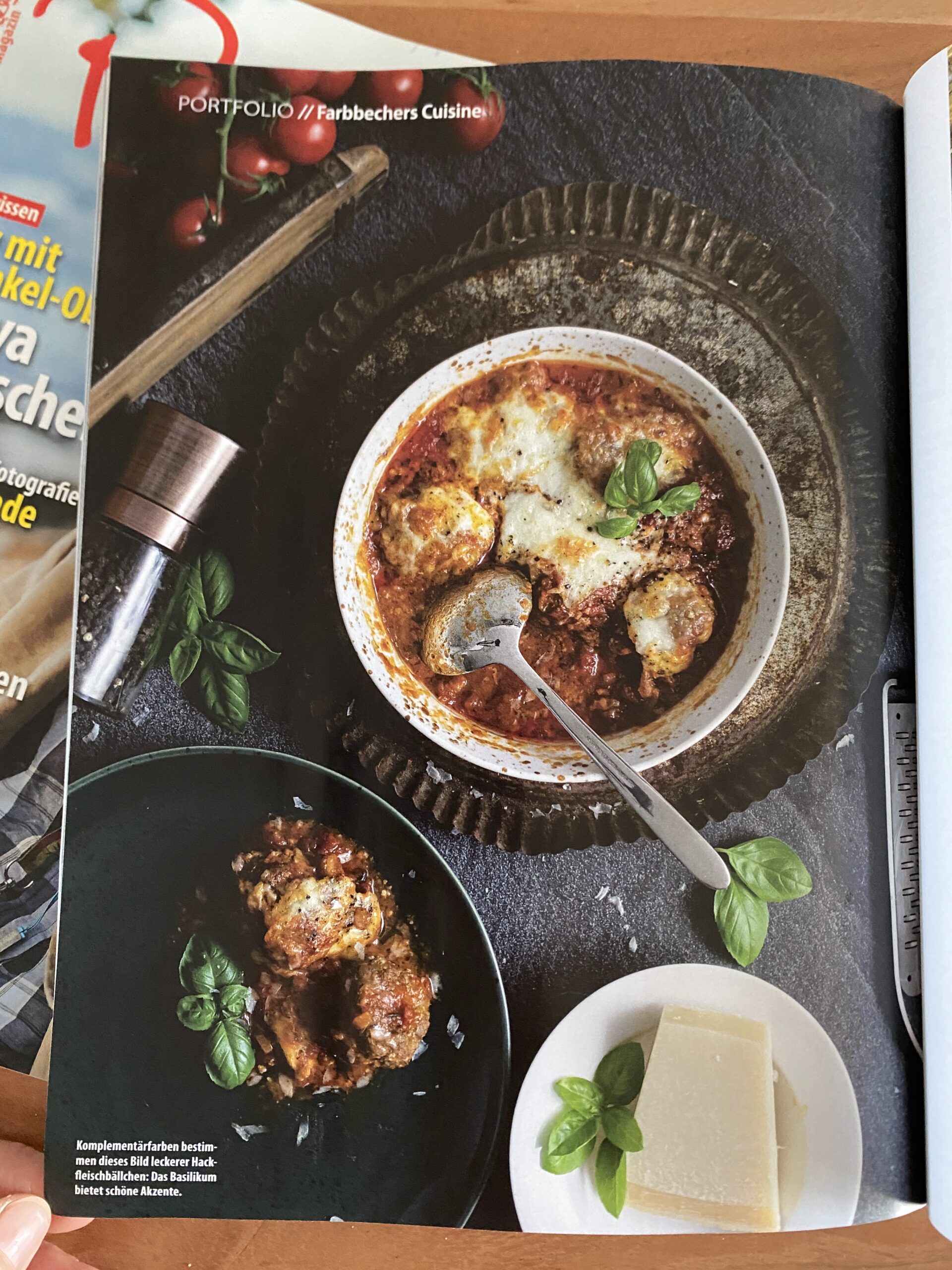 Pictures-Magazin-5 Hackfleischbällchen in Tomatensauce mit Käse überbacken, serviert mit Basilikum. Daneben Parmesan auf einem Teller.