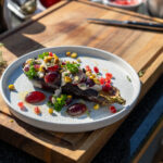 Gegrillte Auberginenhälfte mit Joghurt, Granatapfelkernen, Trauben und Kräutern auf einem Teller auf Holzbrett.