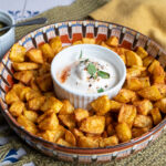 Knusprige Kartoffelwürfel aus der Heißluftfritteuse (Airfryer) mit cremigem Dip, serviert in einer Schale von oben fotografiert.