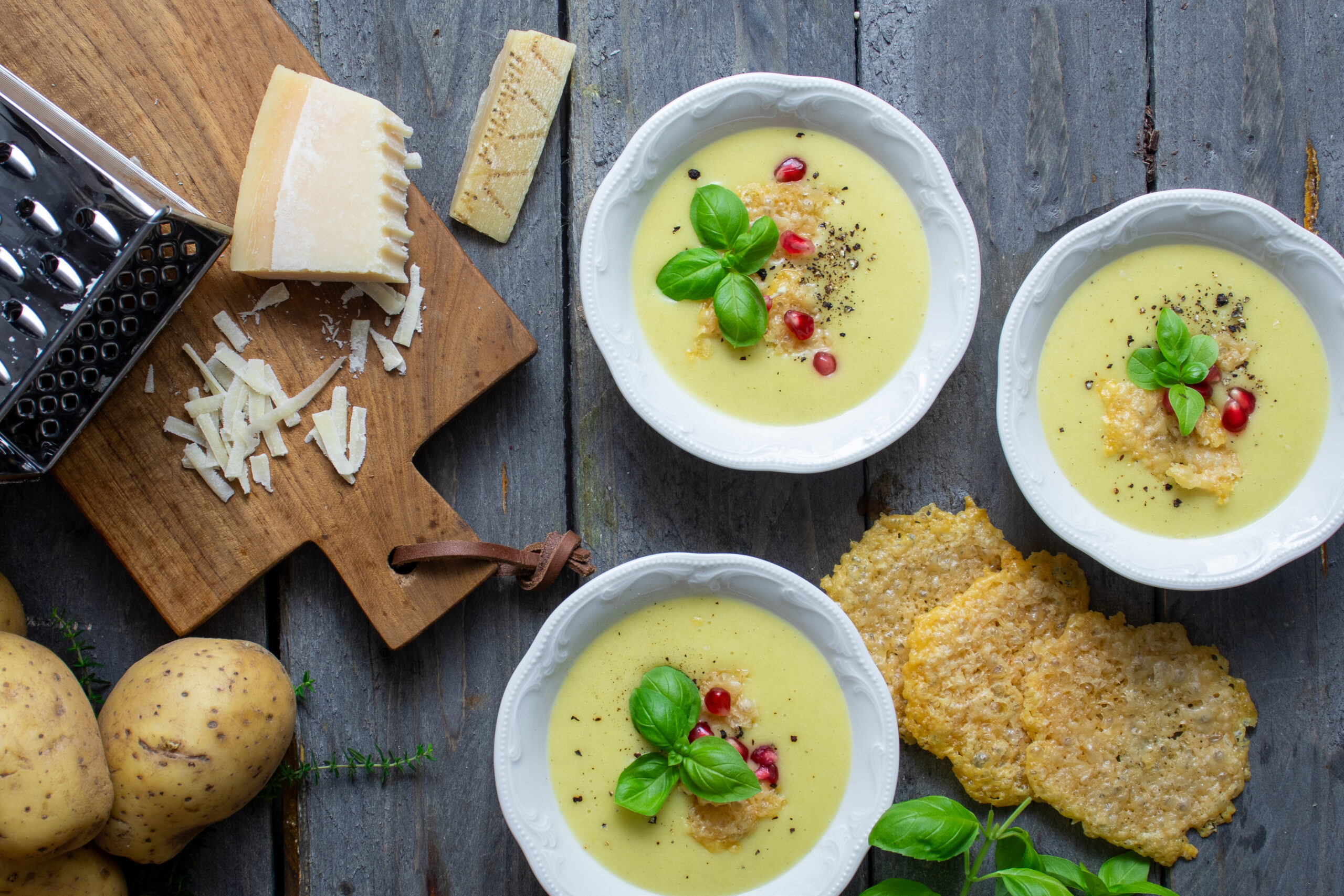 Parmesansuppe_1 remige Parmesansuppe mit Kartoffeln und Lauch, serviert mit Parmesanchips, frischem Basilikum und Granatapfelkernen