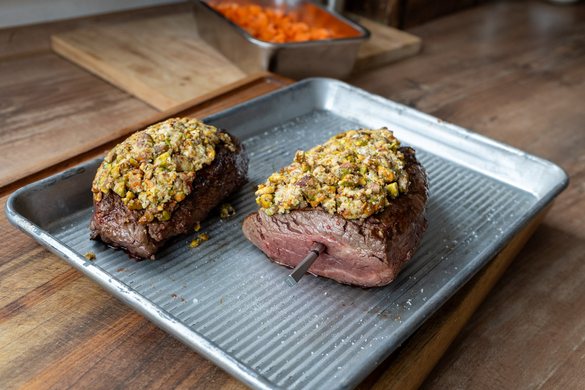 Rinderfilet-02 Zwei gebratene Fleischstücke mit Kruste auf einem Backblech; eines mit Fleischthermometer.