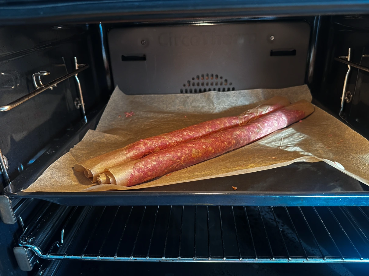Rohes Hackfleisch in Pergamentpapier gewickelt auf einem Backblech in einem Ofen.