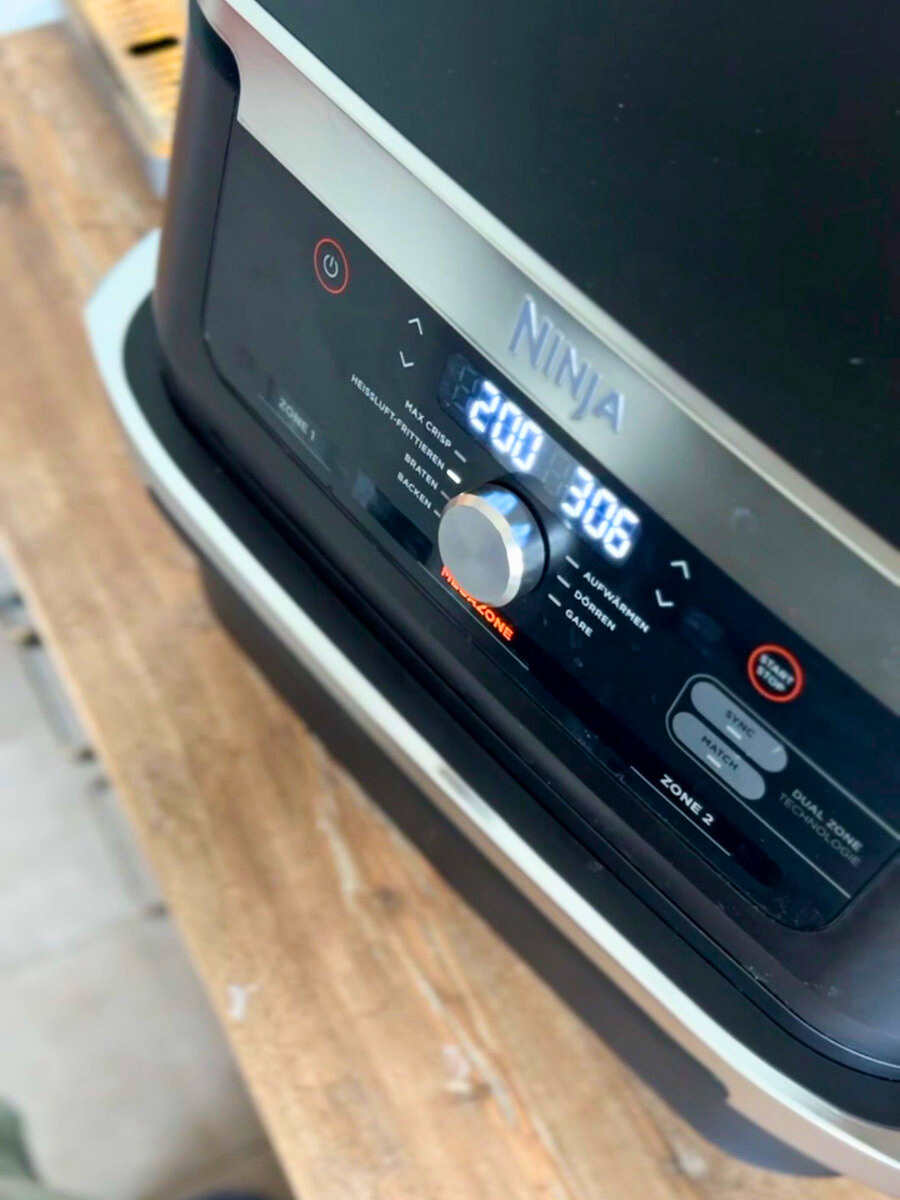 Heißluftfritteuse-richtig-nutzen-05 Küchengerät mit digitaler Anzeige zeigt 200 Grad und 30:6 Minuten auf einem Holzuntergrund.