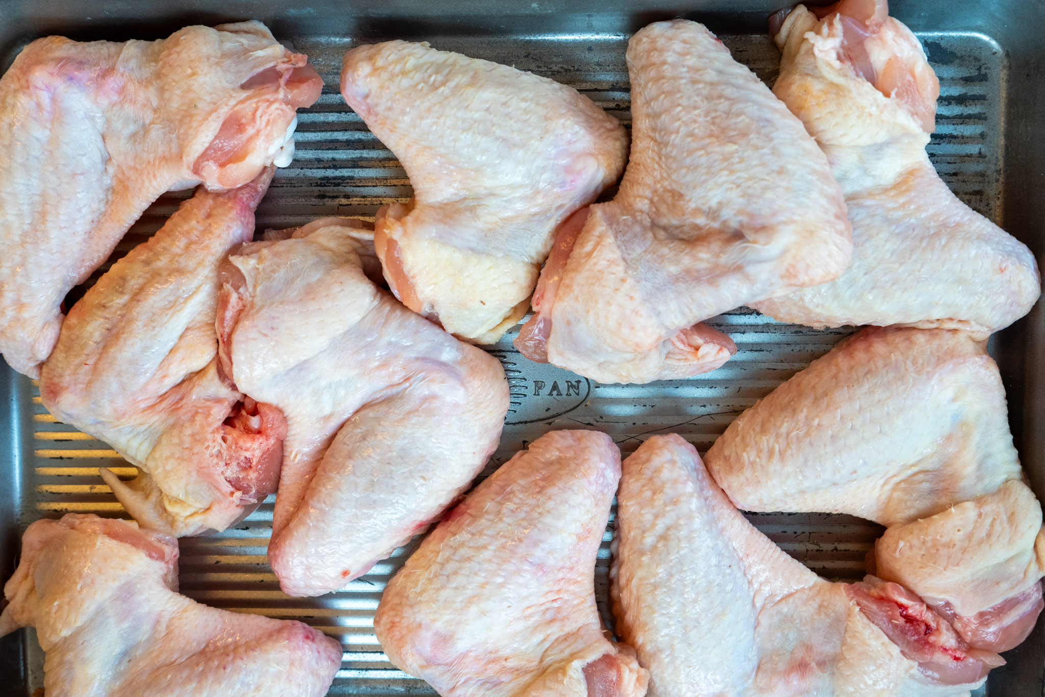 Buffalo-Chicken-Wings-02 Rohes Hähnchenfleisch, speziell Flügel, ordentlich auf einem Backblech platziert.