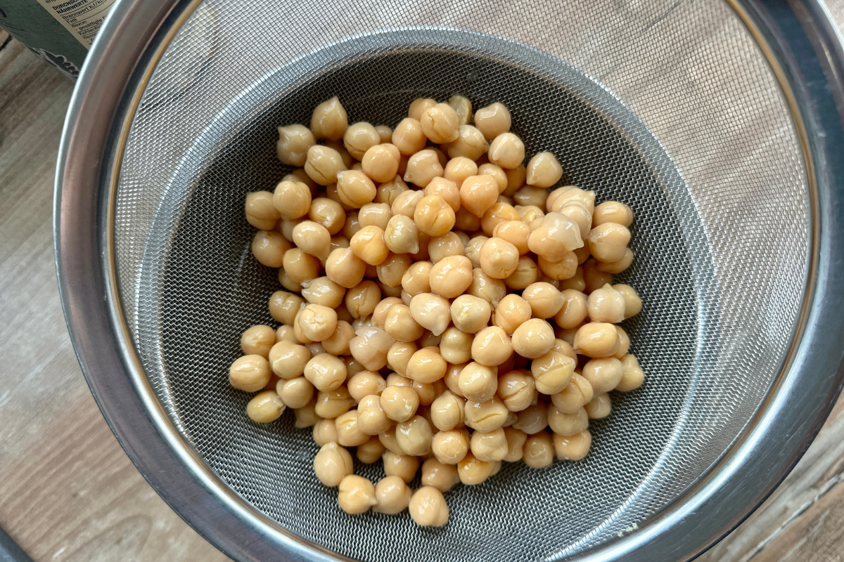 Gewürfelter, gebratener Tofu in einer Heißluftfritteuse auf schwarzem Gittereinsatz, auf einem Holztisch stehend.