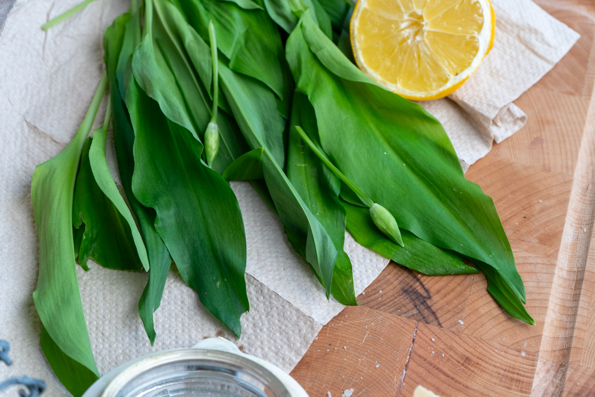 Nudeln mit Spinat in grüner Schale auf Holztisch, leicht mit Pfeffer bestreut.
