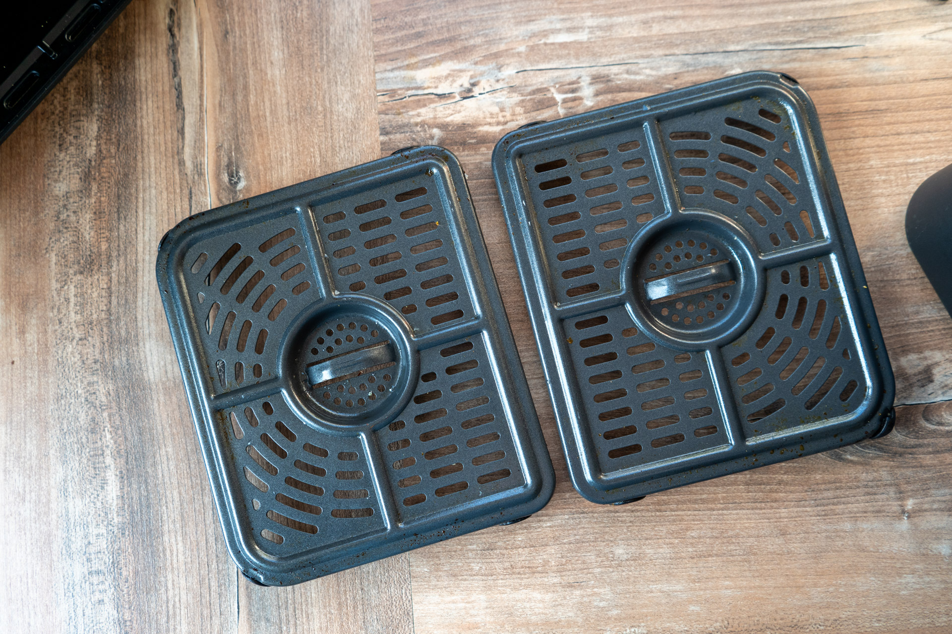 Ninja Foodi FlexDrawer AF500EU Test_4 Zwei schwarze Grillplatten mit Gittermuster auf einem Holztisch.