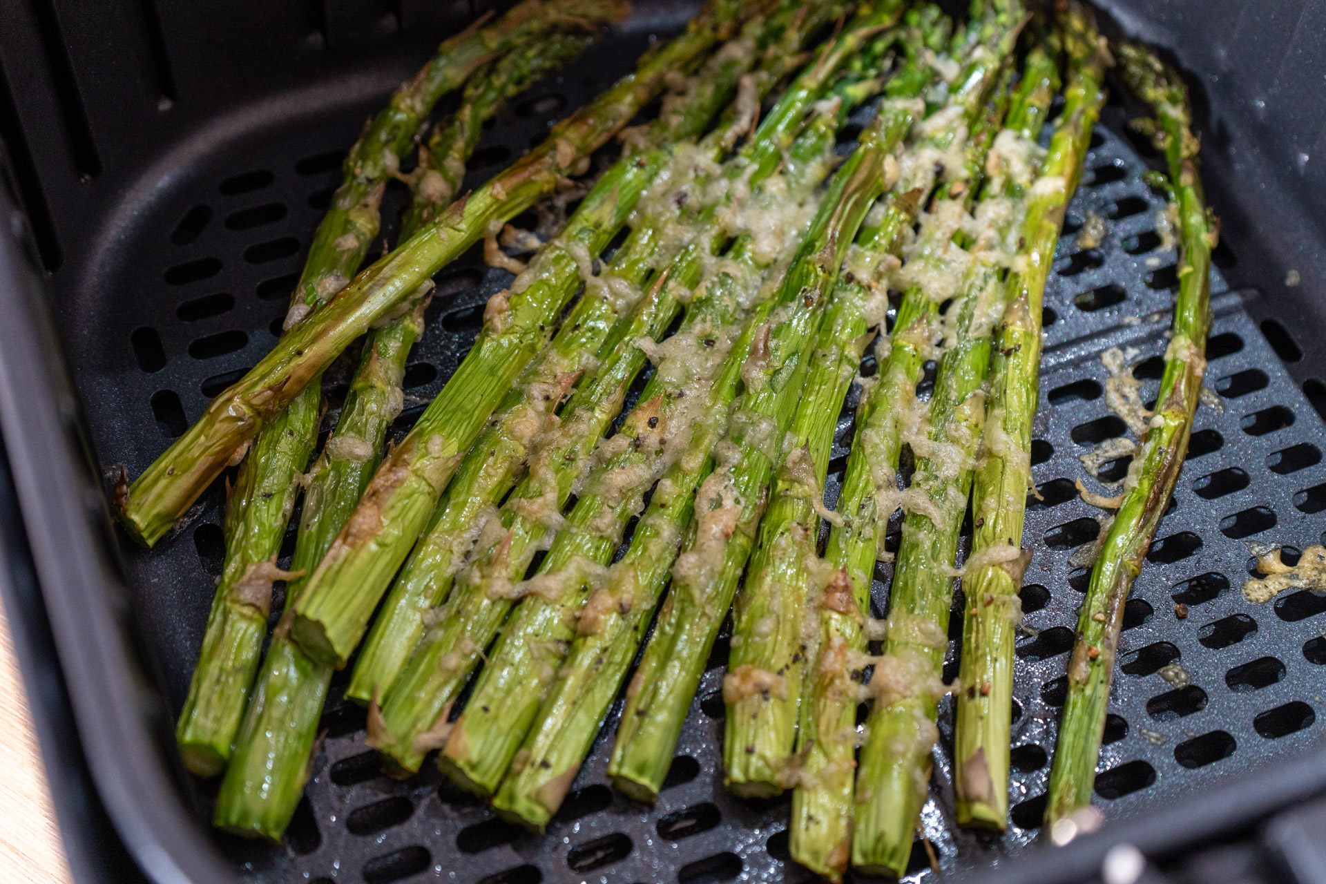 Grüner Spargel mit geschmolzenem Käse in einer Heißluftfritteuse geröstet.