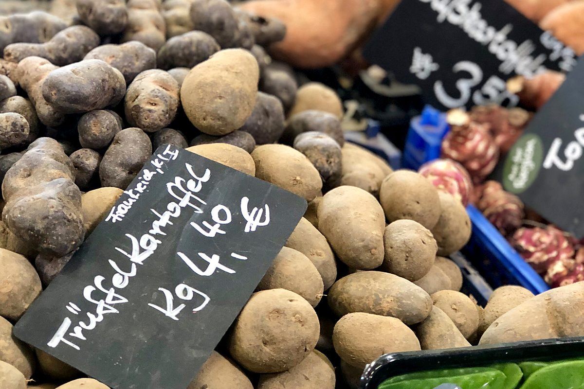 herbstkueche-kartoffeln-markt-quer Packung mit geschnittenem Bündnerfleisch auf einem Holztisch, Etikett in rötlicher Schrift.