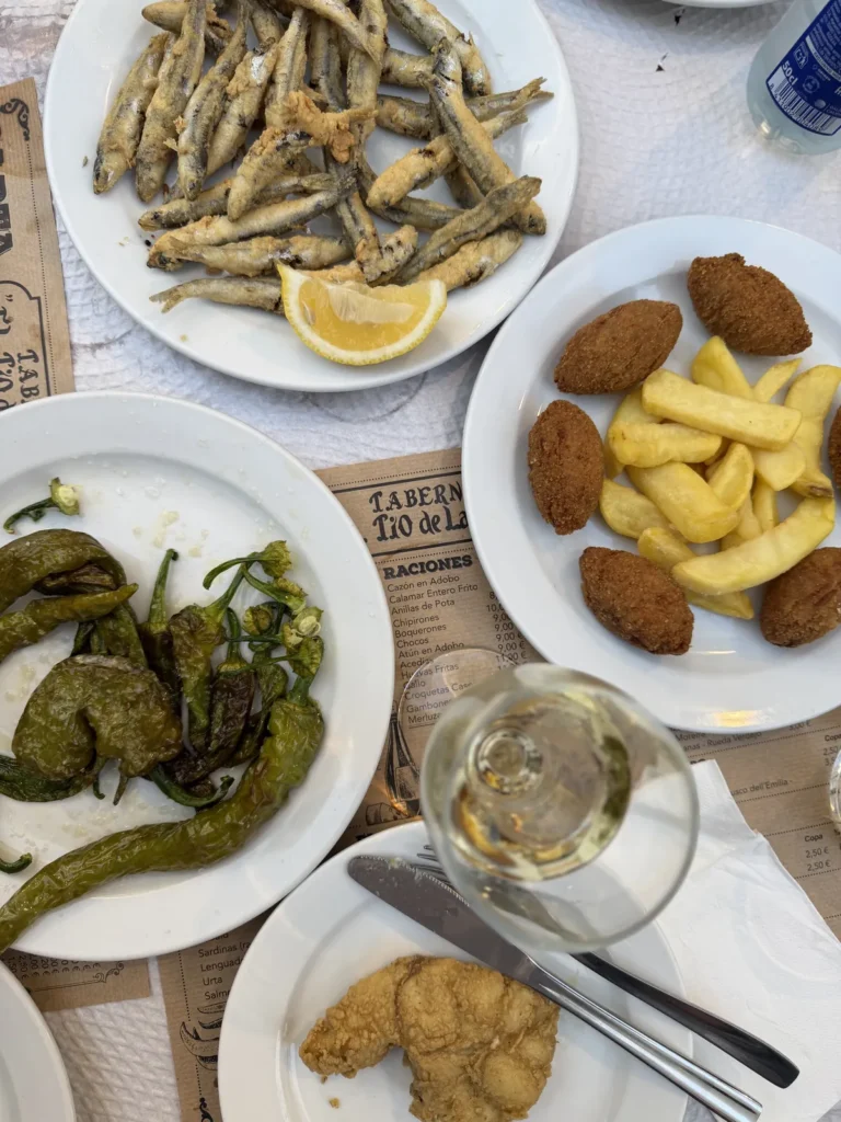 Tisch in der Taberna El Tío de la Tiza mit frittierten Sardellen, frittiertem Fisch, Croquetas mit Pommes, Pimientos fritos und Weißwein.