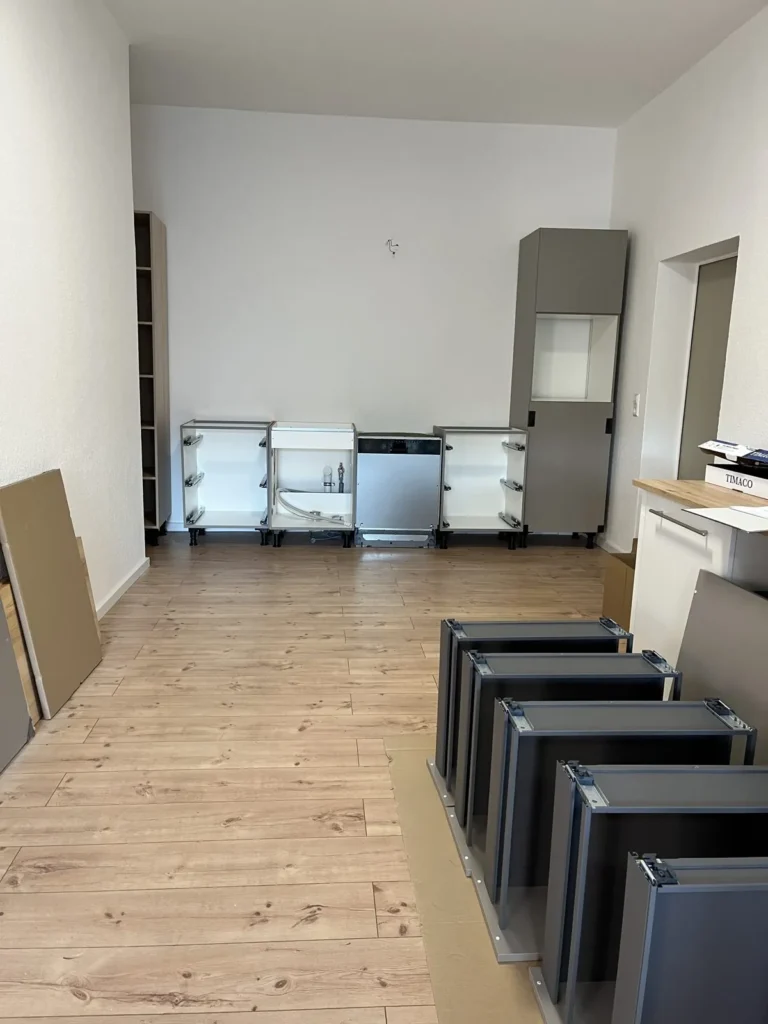 Küchenzeile im Aufbau mit Schränken und Geräten am Boden