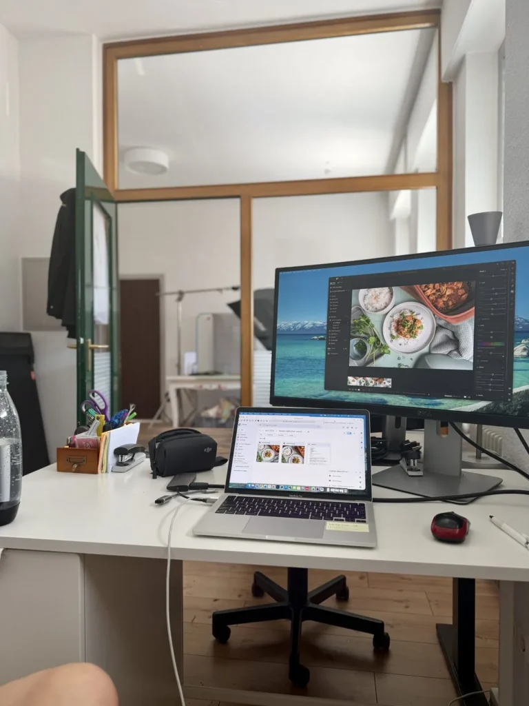Büro mit Schreibtisch und Monitor hinter einer Glasfront mit Holzrahmen