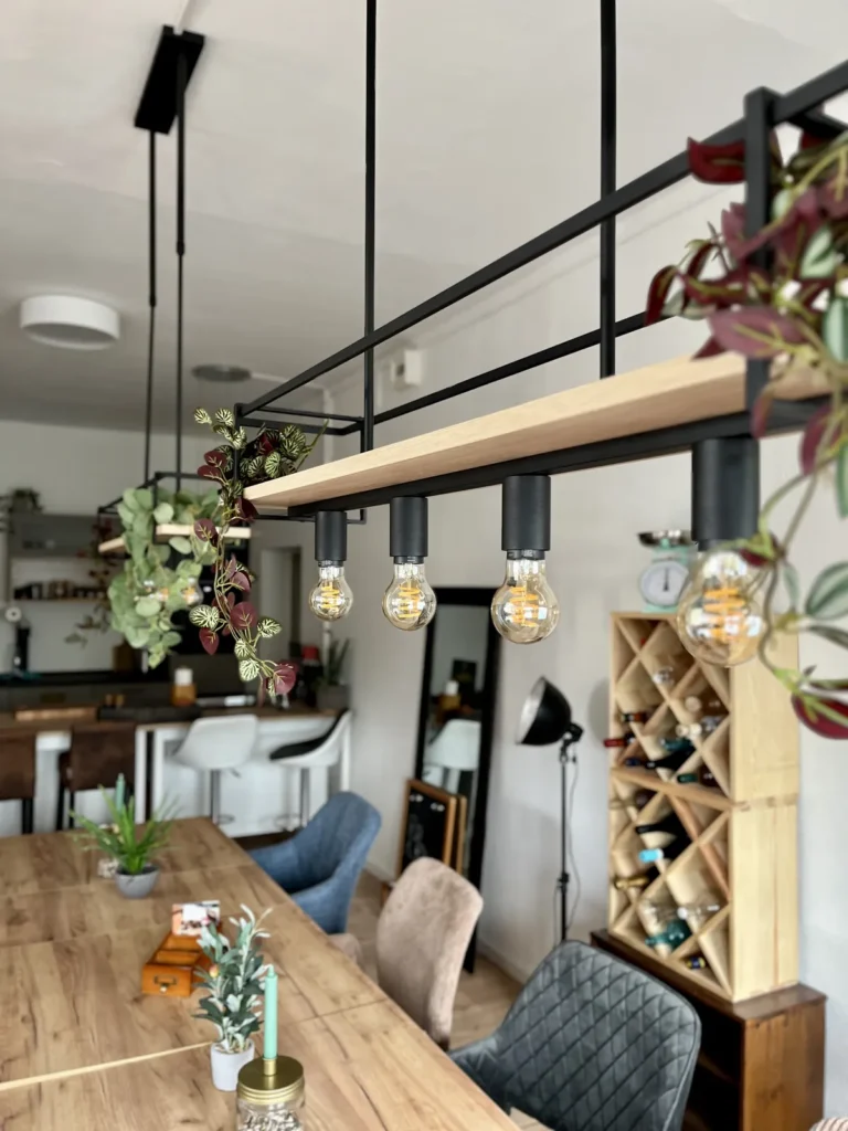 Dimmbare Hängelampen über der Tafel, daneben ein Weinregal
