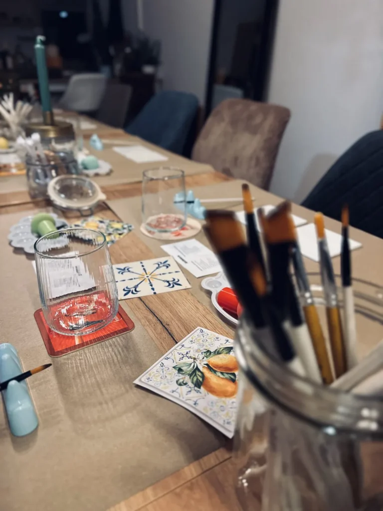 Tafel mit Pinseln, Farben und Weingläsern beim Afterwork-Abend Paint and Drink