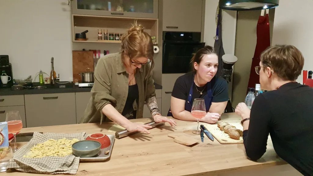 Christina Becher zeigt zwei Teilnehmerinnen beim Pastakurs, wie Nudeln geformt werden