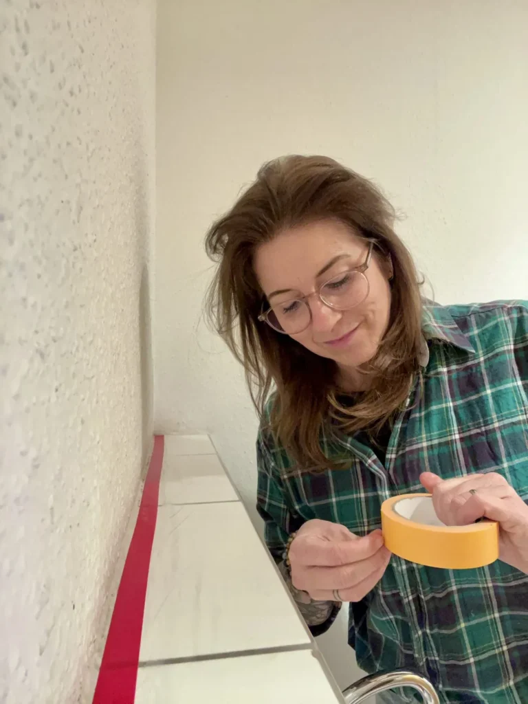 Christina Becher klebt beim Renovieren Malerkrepp an die Wand