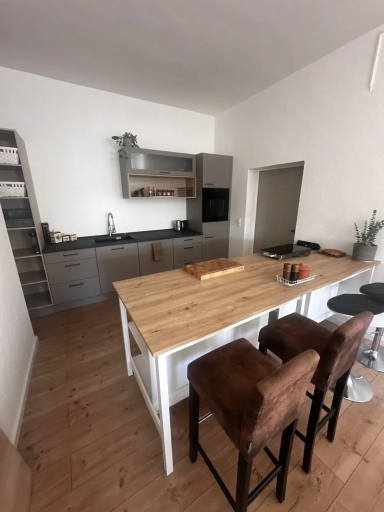 Showküche mit Holz-Arbeitsfläche, Barhockern und Hängeschränken in der Foodlocation