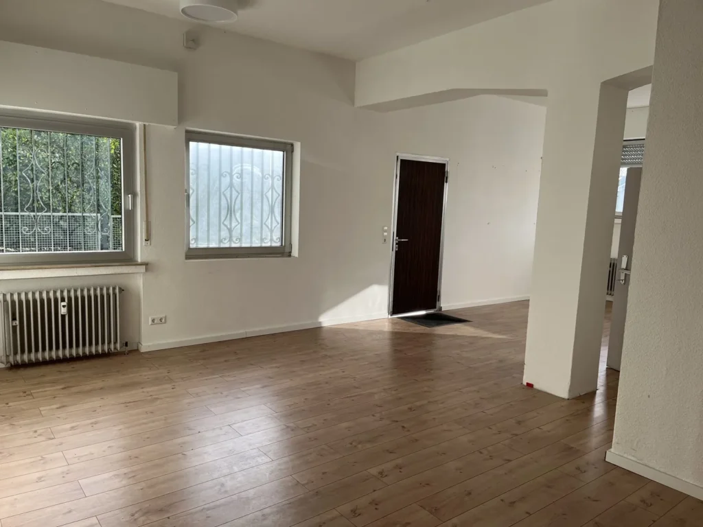 Leere, helle Räume mit Laminatboden und vergitterten Fenstern vor der Renovierung