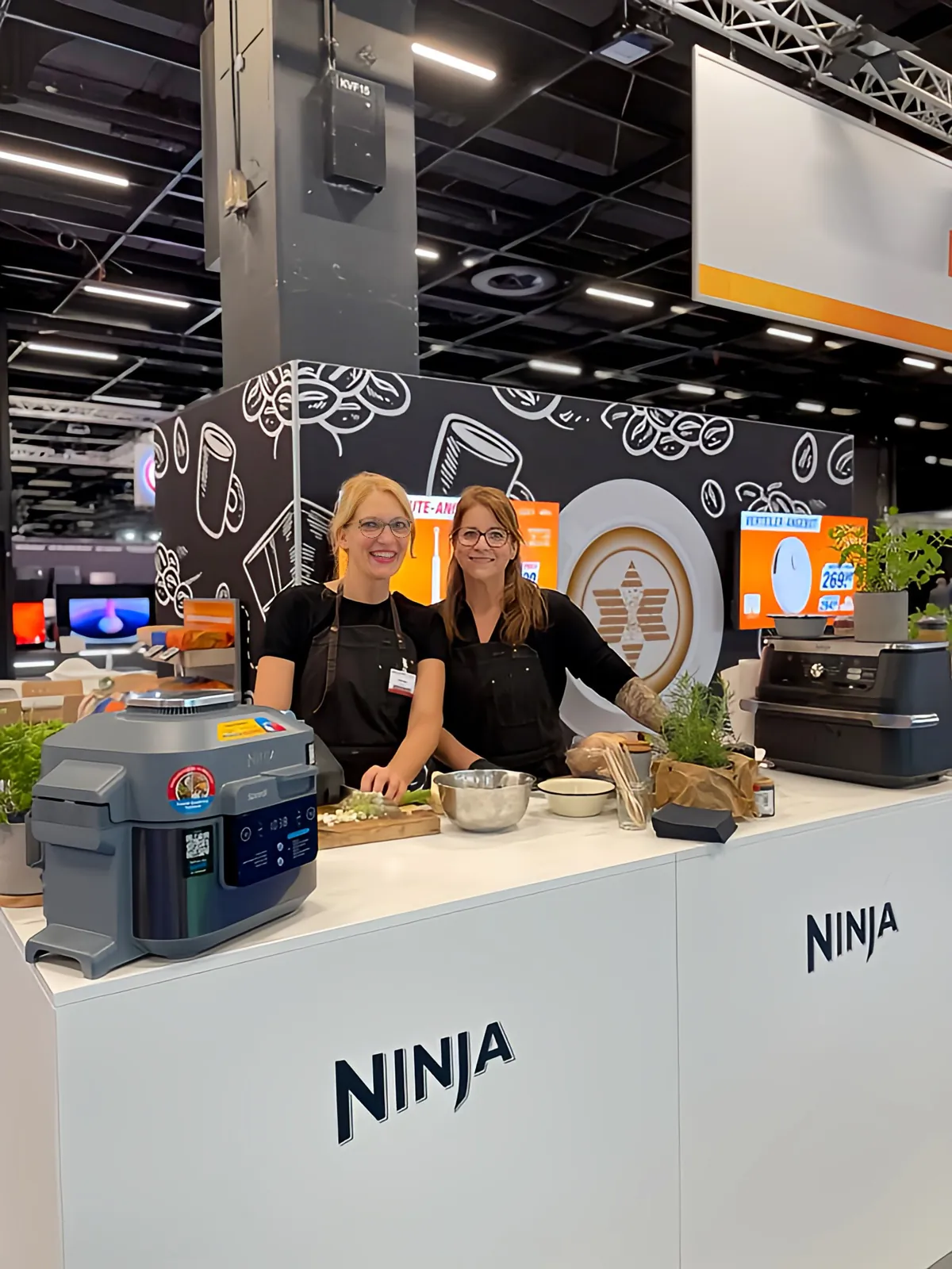 Christina Becher und eine Kollegin am Ninja-Stand der Expert Messe 2023 in Köln, auf dem Tresen ein Ninja Speedi.